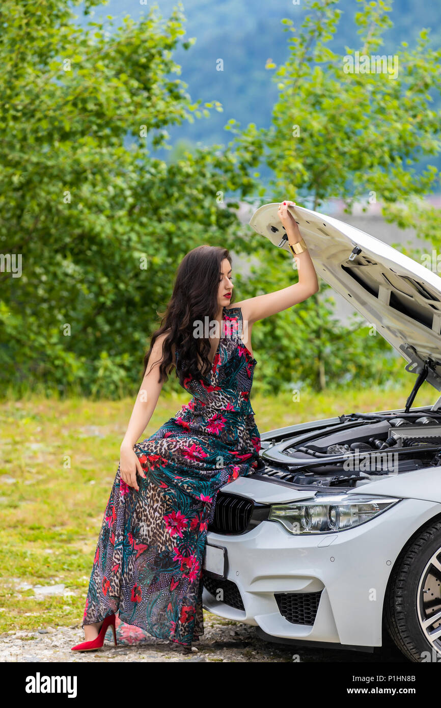 Young woman waits for assistance near her car broken down on the road side. Stock Photo