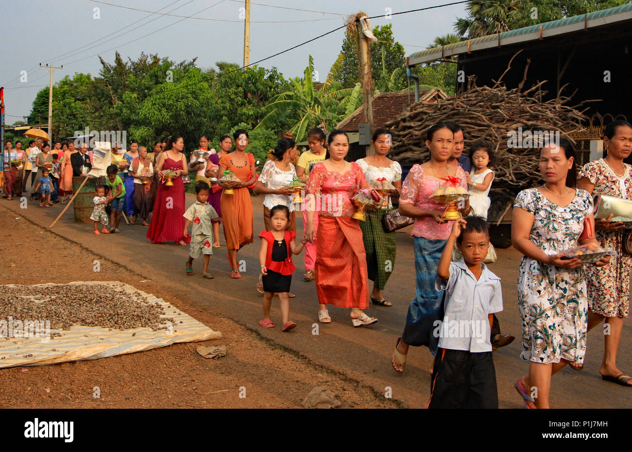 Guests to a Cambodian wedding walk to the bride's house bearing gifts in the early morning sunshine. Stock Photo