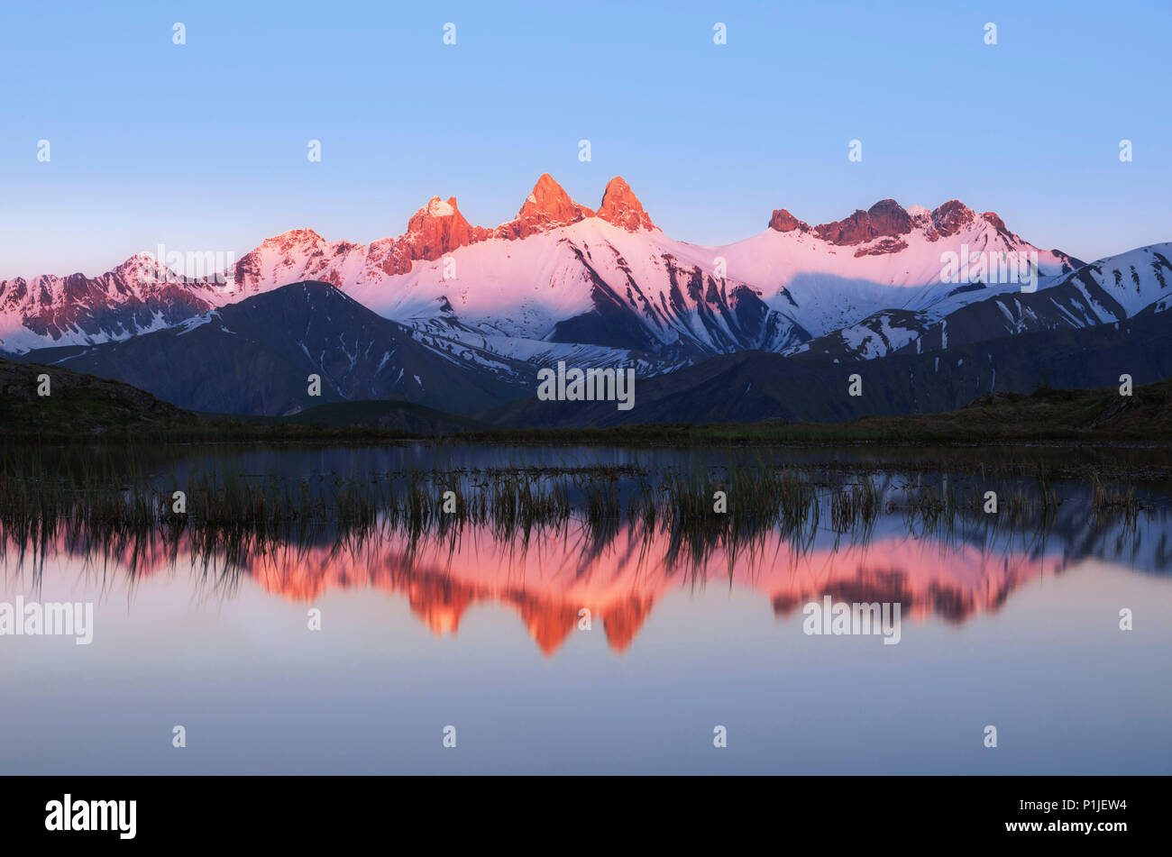 Mountain peaks with alpenglow in the French Alps mirrored in the mountain lake, Aiguille d'Arves, Hautes-Alpes, Alps, France Stock Photo