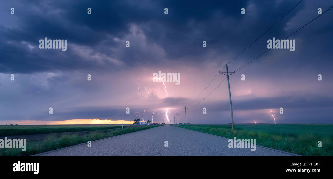 Cloud-to-ground lightnings of a thunderstorm at sunset above a highway in Kansas, USA Stock Photo