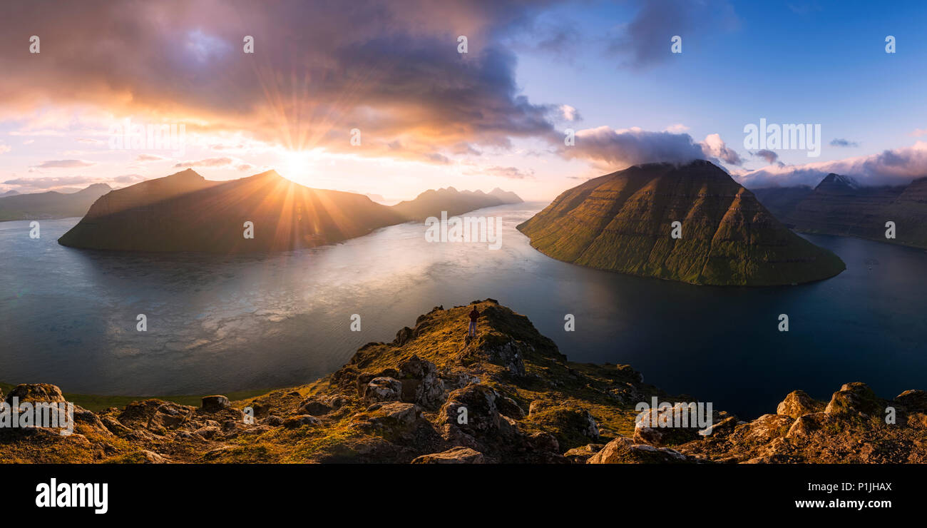 Hiker over the fjords of the Faroe Islands at sunset, Borðoy, Faroe Islands, Denmark Stock Photo