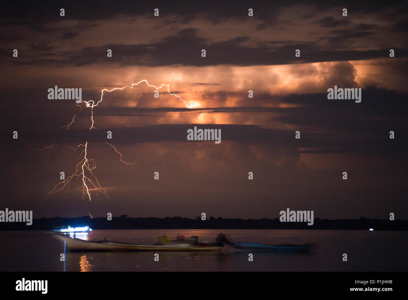 Distant positive cloud-to-ground discharges behind fisher boats on lake Maracaibo (Catatumbo thunderstorm, the place with the highest lightning density worldwide), Ologa, Zulia, Venezuela, South America Stock Photo