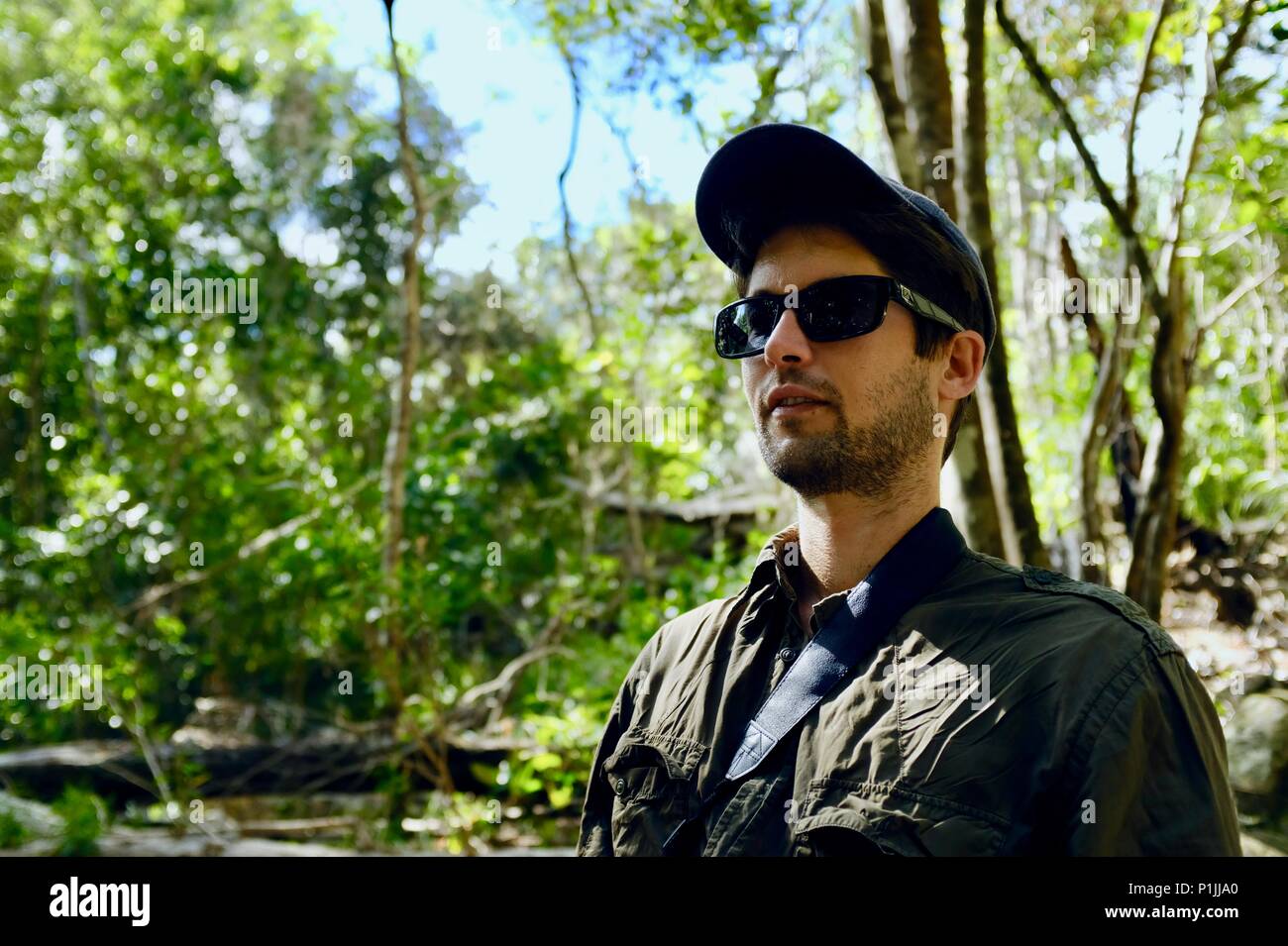 Young man wearing sunglasses and a hat in a forest, Paluma Range ...