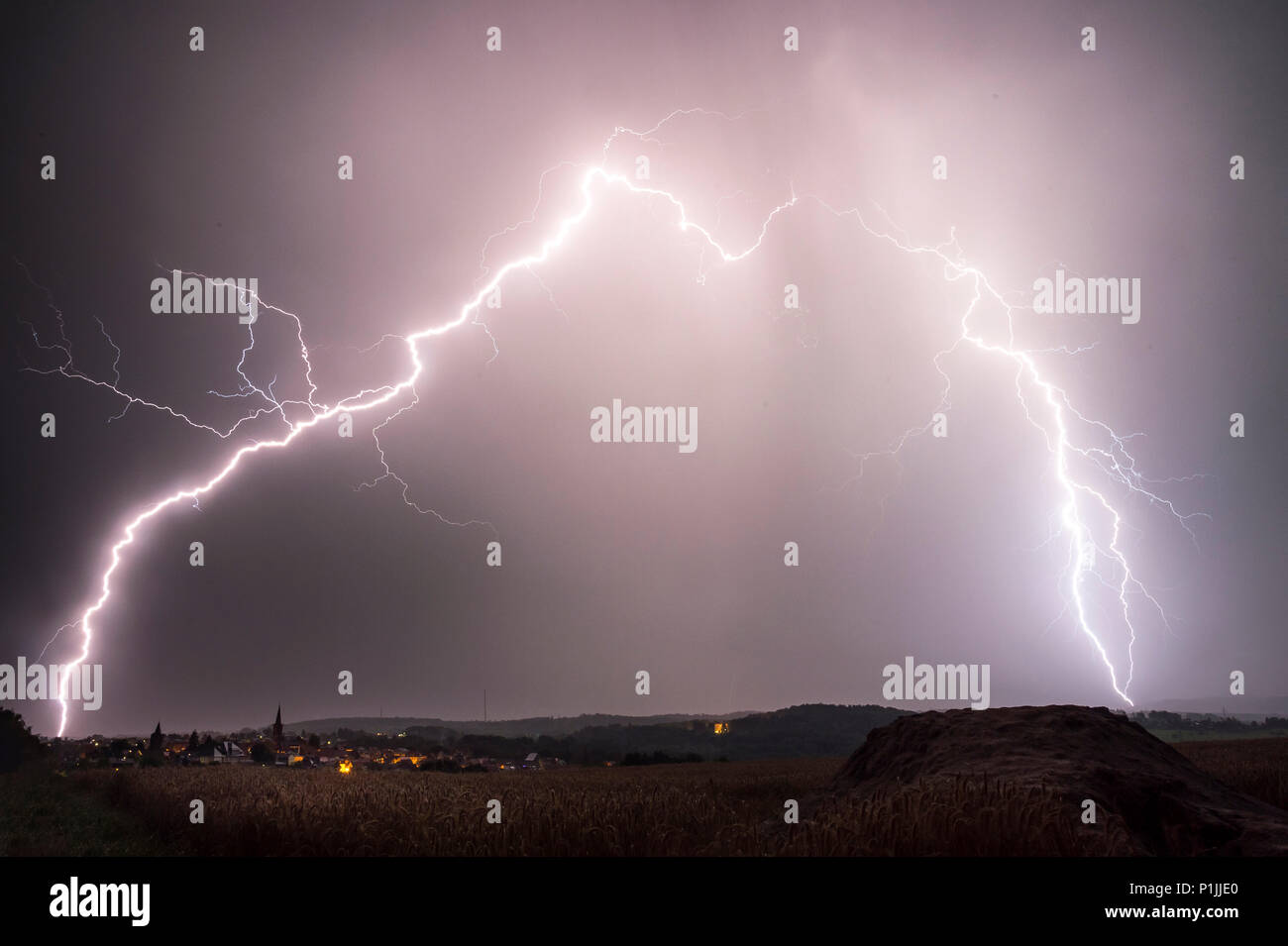 Branched cloud-to-ground lightnings behind the town of Grünberg, Hessia, Germany Stock Photo