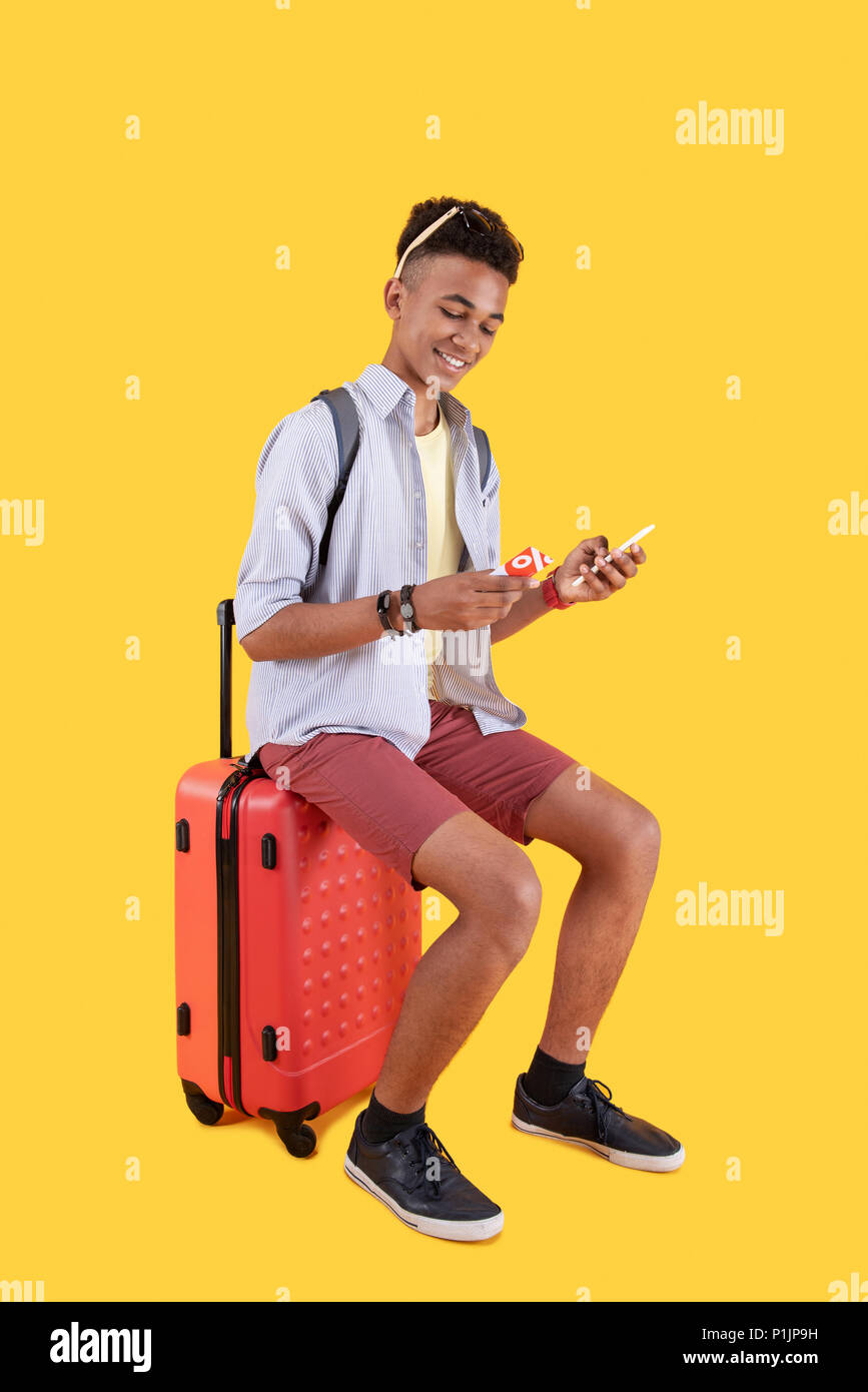 Cheerful positive man sitting on a suitcase Stock Photo