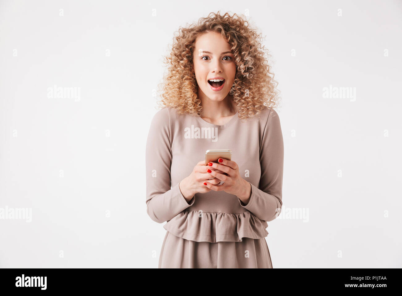 Portrait Of A Cheerful Young Curly Blonde Girl In Dress Holding
