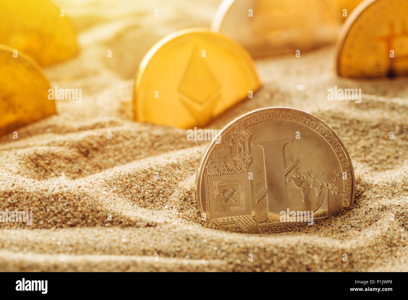 Silver Litecoin coin in sand, conceptual image for lost and found valuable cryptocurrency coins that are standing the test of time. Stock Photo