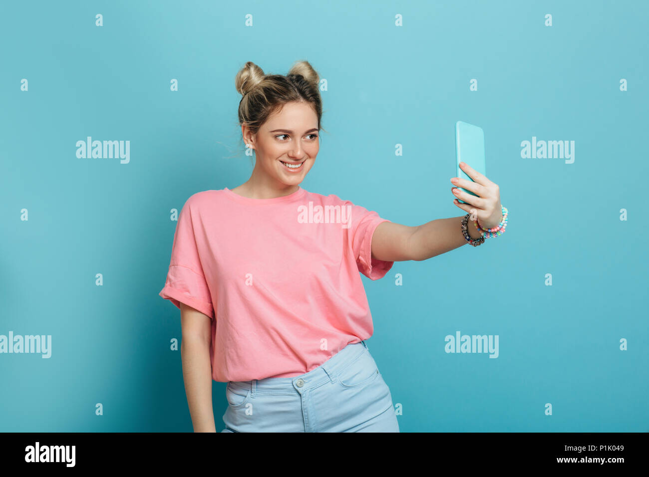 youth trendy woman making photo on her smartphone against a blue pastel background . making cool selfie Stock Photo