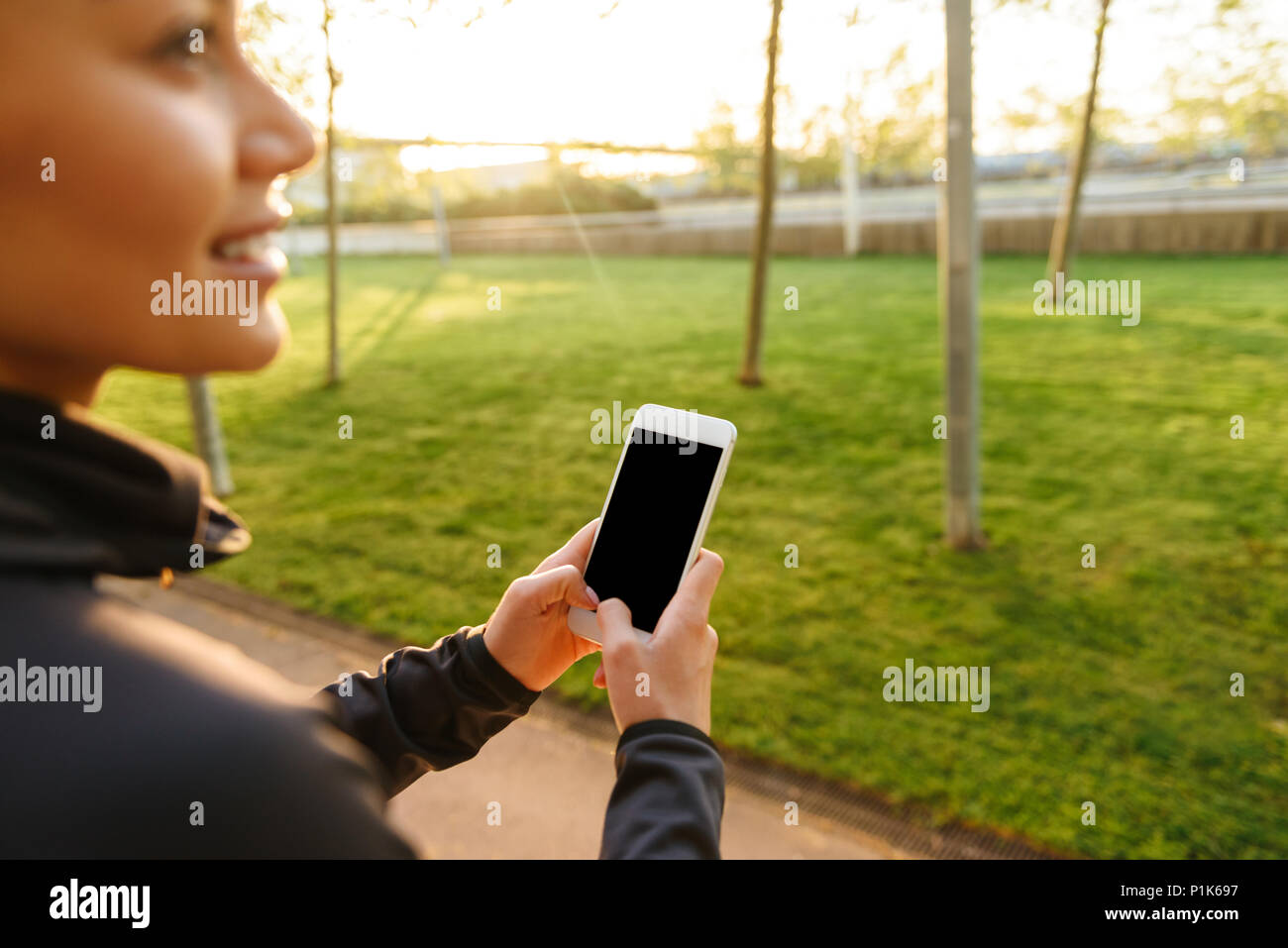 Cropped photo of young sports woman using mobile phone outdoors. Stock Photo