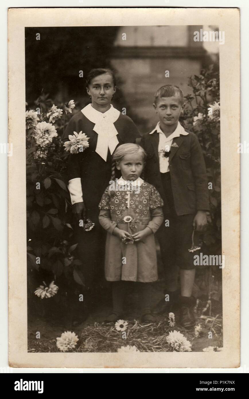 GERMANY - CIRCA 1940s: Vintage photo shows young woman with children (boy and girl) pose in the garden. Black & white antique photography. 1940s. Stock Photo