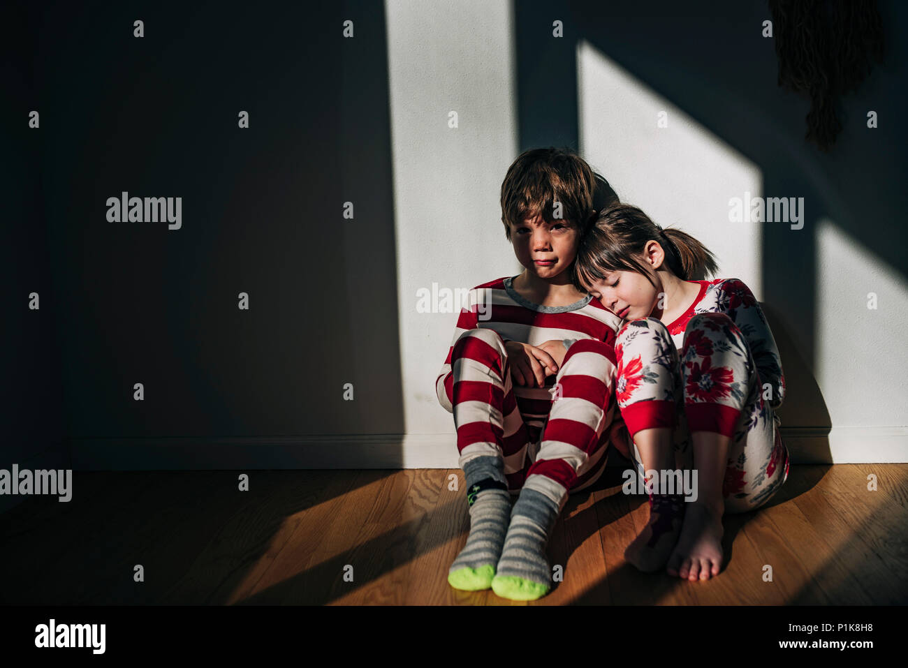 Brother and sister sitting on the floor in their pyjamas Stock Photo