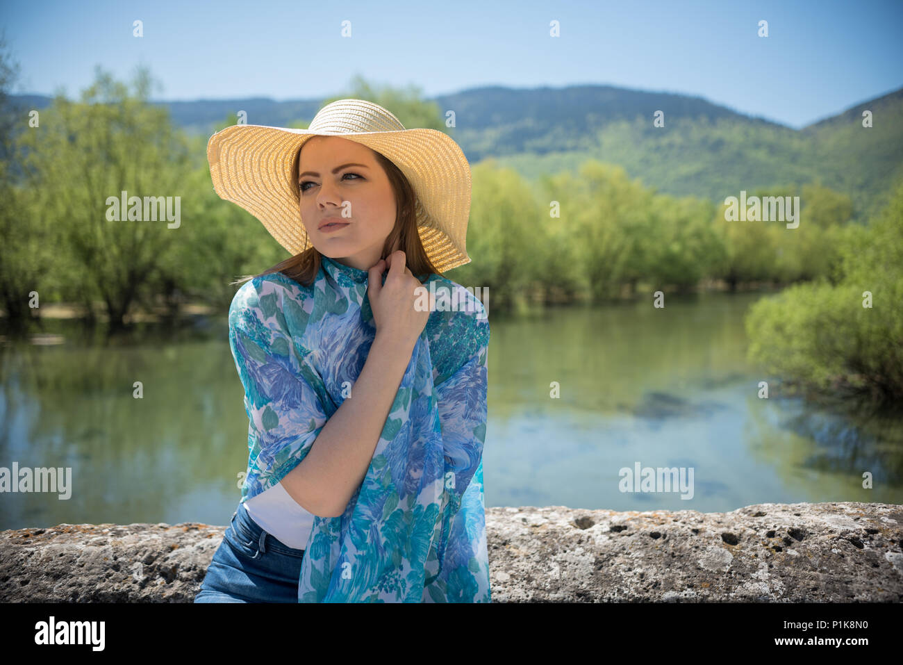 Portrait of a woman wearing a sunhat sitting by a river Stock Photo