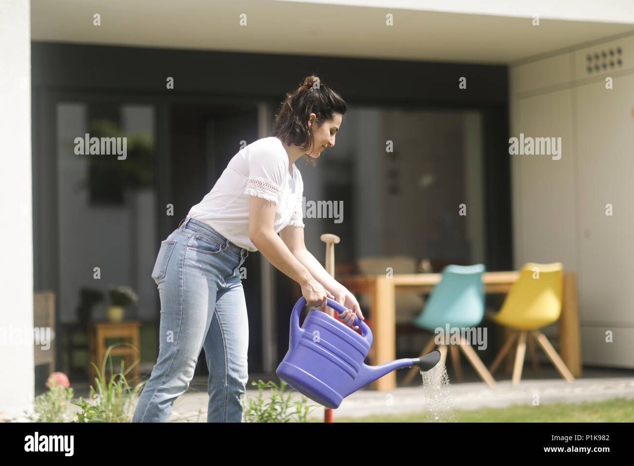 Woman watering flowers in her garden Stock Photo - Alamy