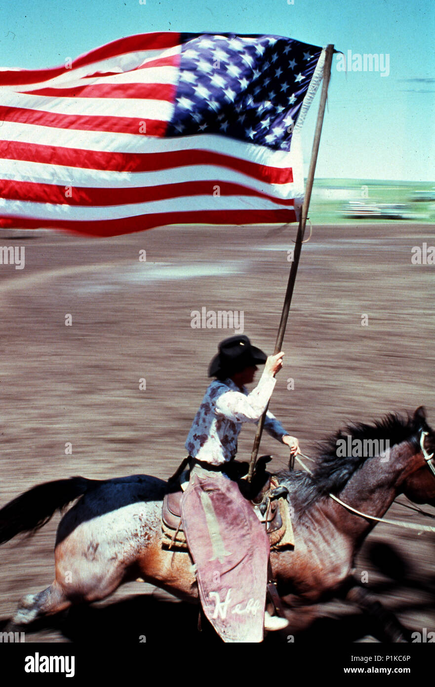 Cowboy riding on a horse flying the American flag during a rodeo