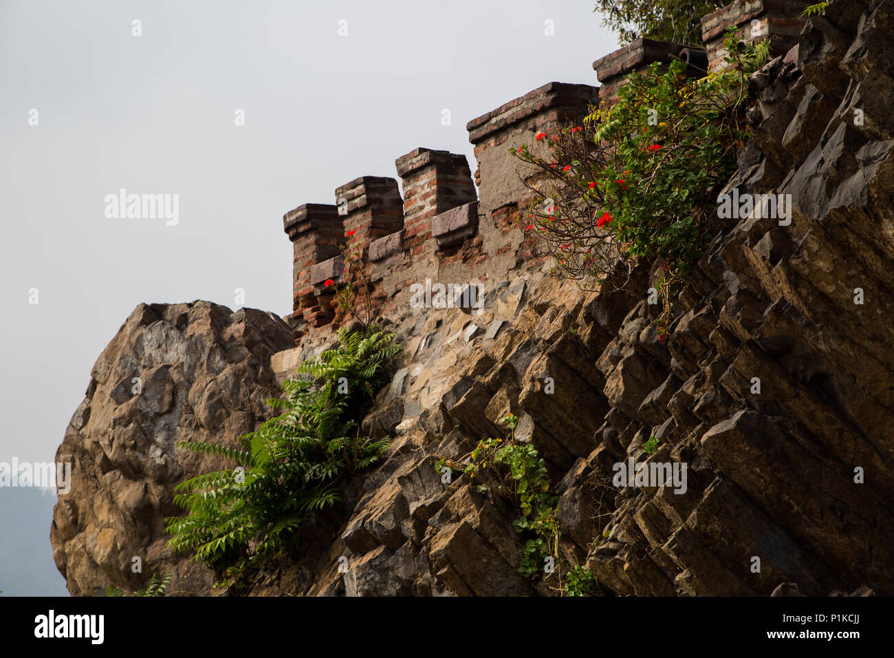 A crenelated wall jutting out of the rock face at Castillo Hidalgo on Santa Lucia Hill in Santiago, Chile. Stock Photo