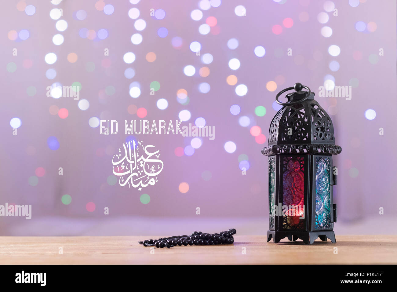 Eid al-Fitr Mubarak Greeting Typography with Bokeh backgound. Antique fanoos and Islamic Prayer Beads on wooden board Stock Photo