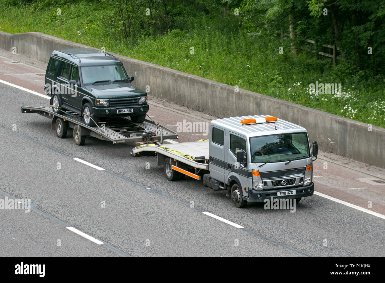 2005 green Land Rover Discovery SUV Vehicle 24hr breakdown recovery transportation, Shipping freight, Haulage truck trailer on-tow, M6 at Lancaster, UK Stock Photo