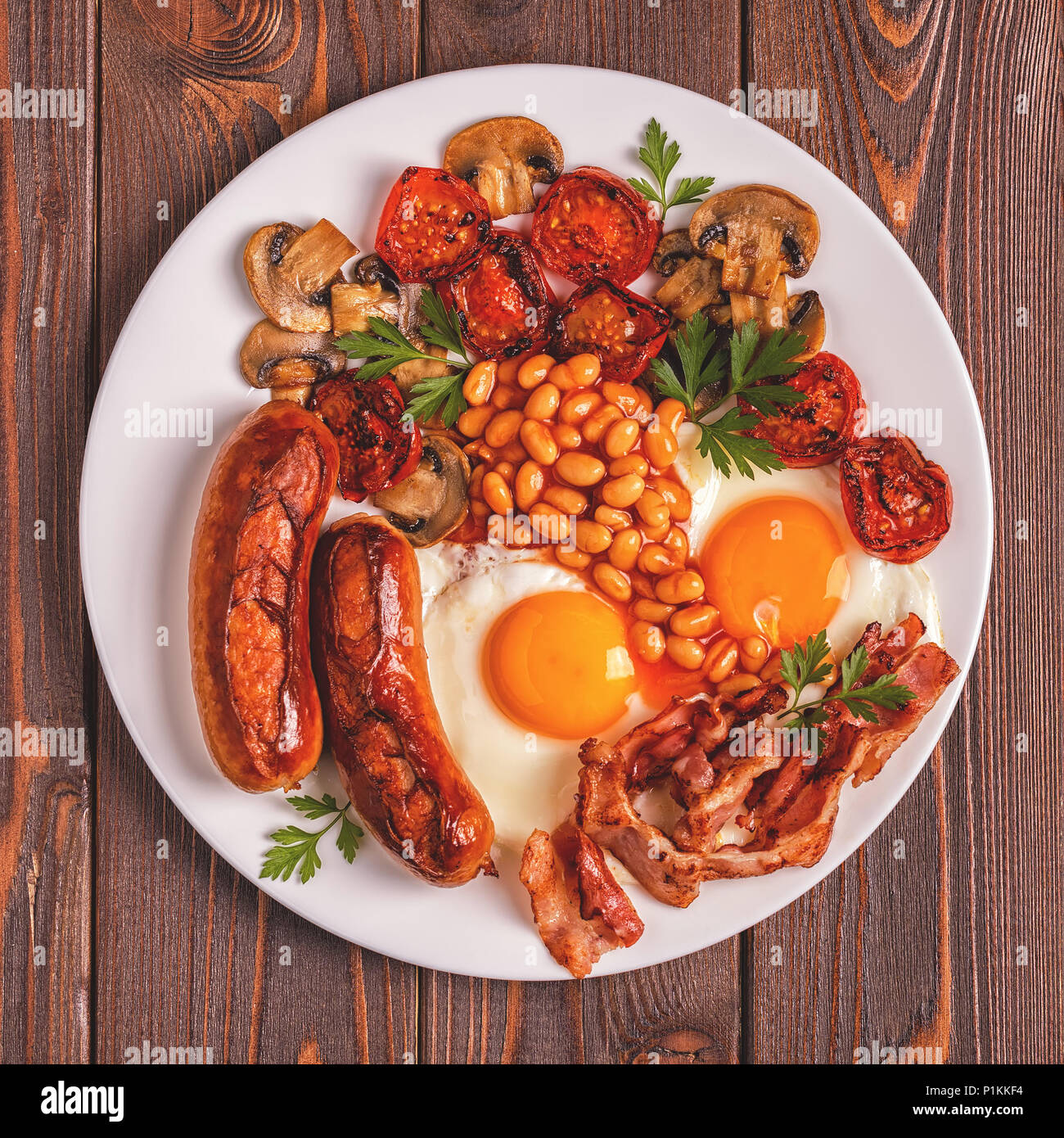 Traditional full English breakfast with fried eggs, sausages, beans,  mushrooms, grilled tomatoes and bacon on wooden background. Top view Stock  Photo - Alamy