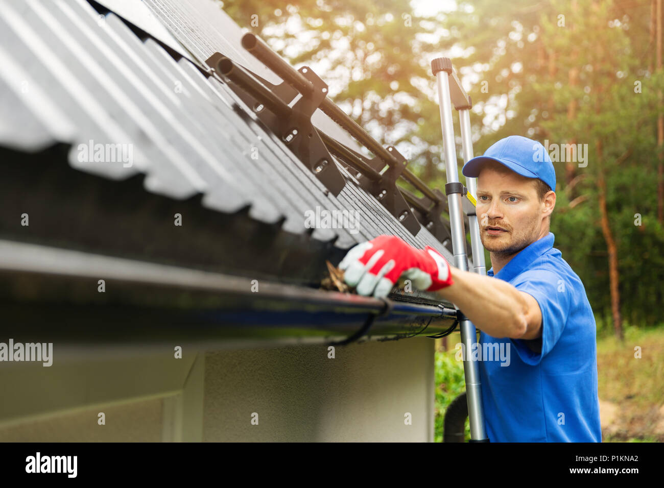 worker cleaning house gutter from leaves and dirt Stock Photo