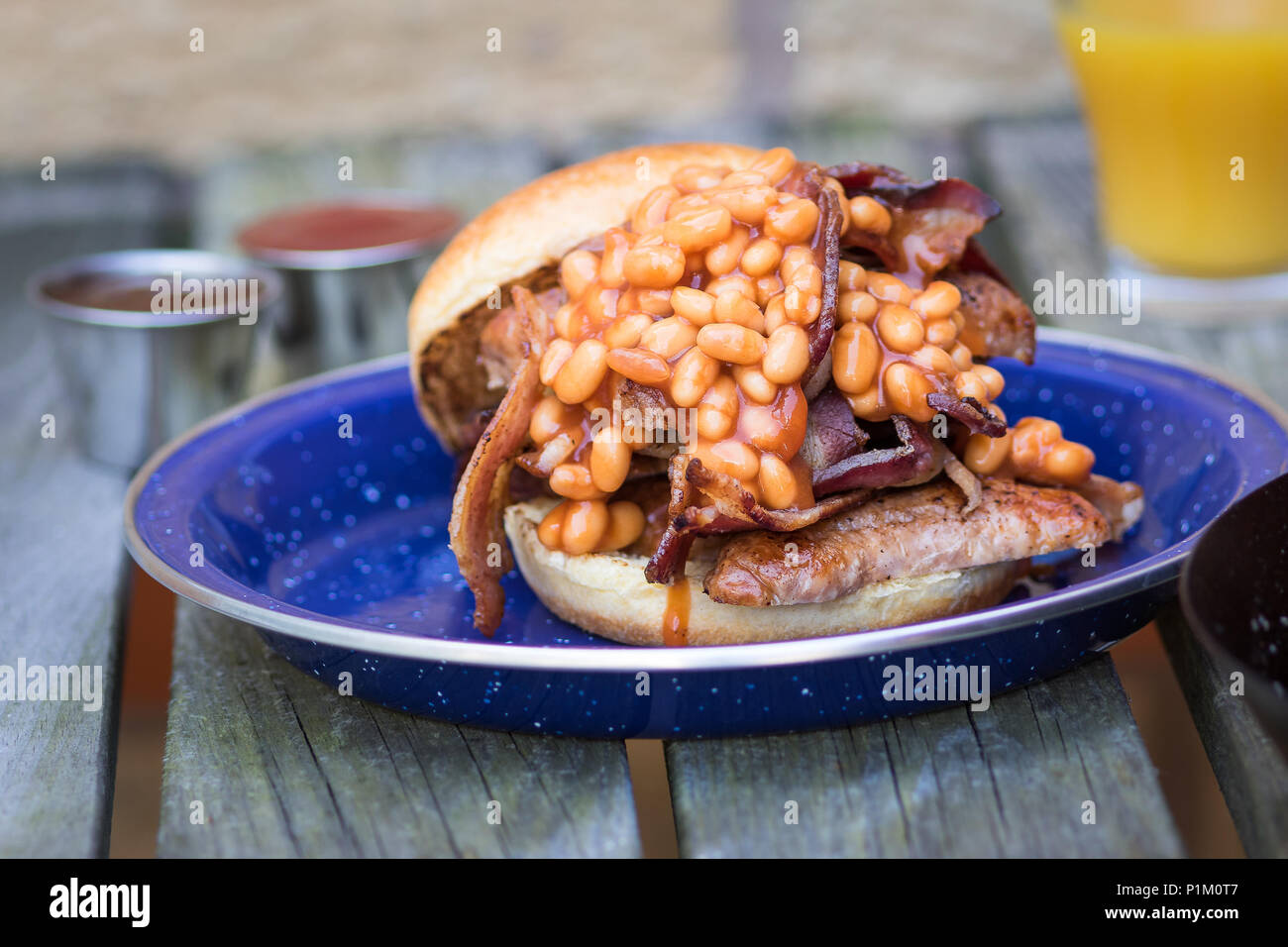 Sausage,Streaky Bacon & Baked Beans served in a brioche bun for breakfast Stock Photo