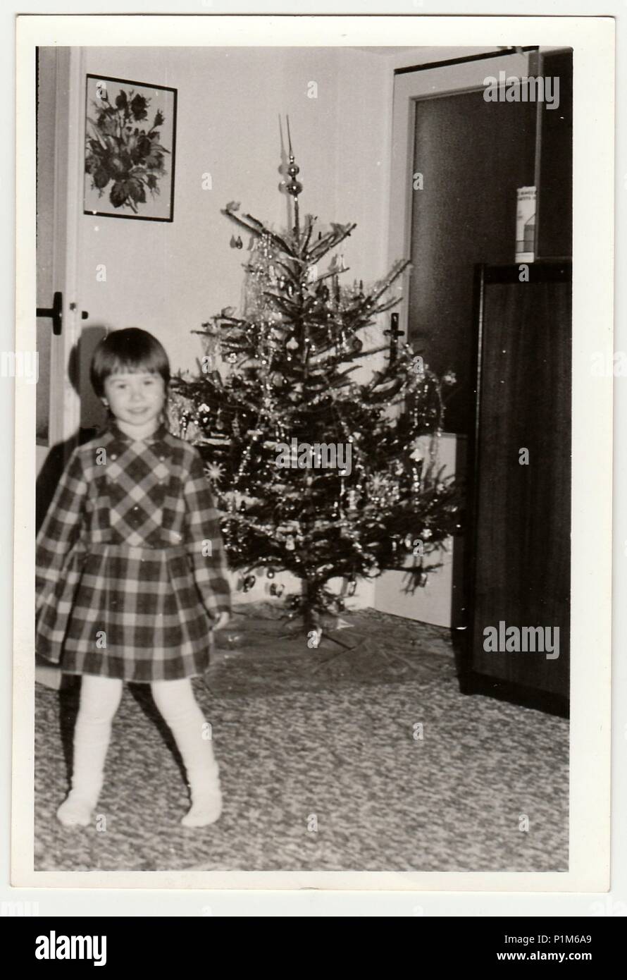 THE CZECHOSLOVAK SOCIALIST REPUBLIC - CIRCA 1970s: Retro photo shows small girl during Christmas. Christmas tree is on background.  Black & white vintage photography. Stock Photo