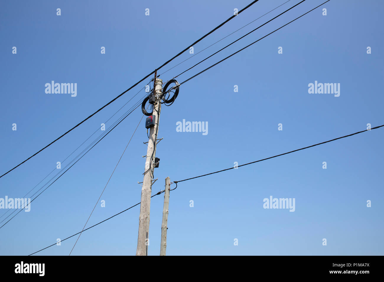 Electricity poles and lines against a blue sky Stock Photo - Alamy