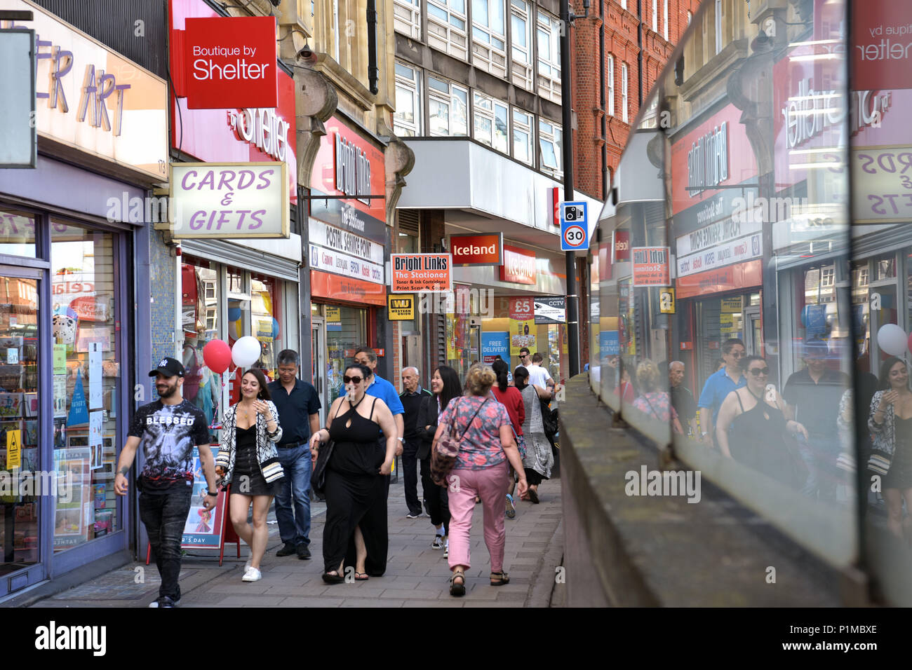 People and shoppers walk past independent and charity shops and a