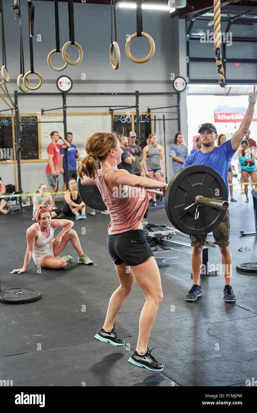 Female or woman competing in a CrossFit fitness challenge competition by dead lifting weights inside a gym in Montgomery Alabama, USA. Stock Photo