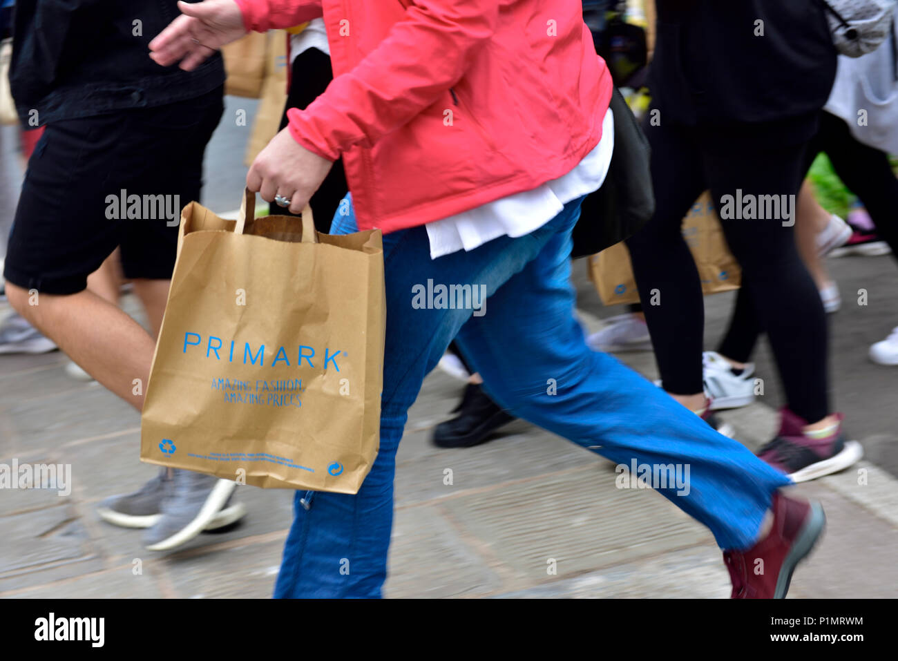 Shopper in a hurry carrying a paper Primark carrier bag Stock Photo