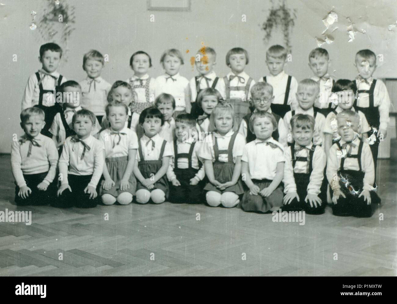 THE CZECHOSLOVAK SOCIALIST REPUBLIC - CIRCA 1960s: Retro photo shows pupils in the classroom. They pose for a group photography. Vintage black & white photography. Original image is damaged. Stock Photo