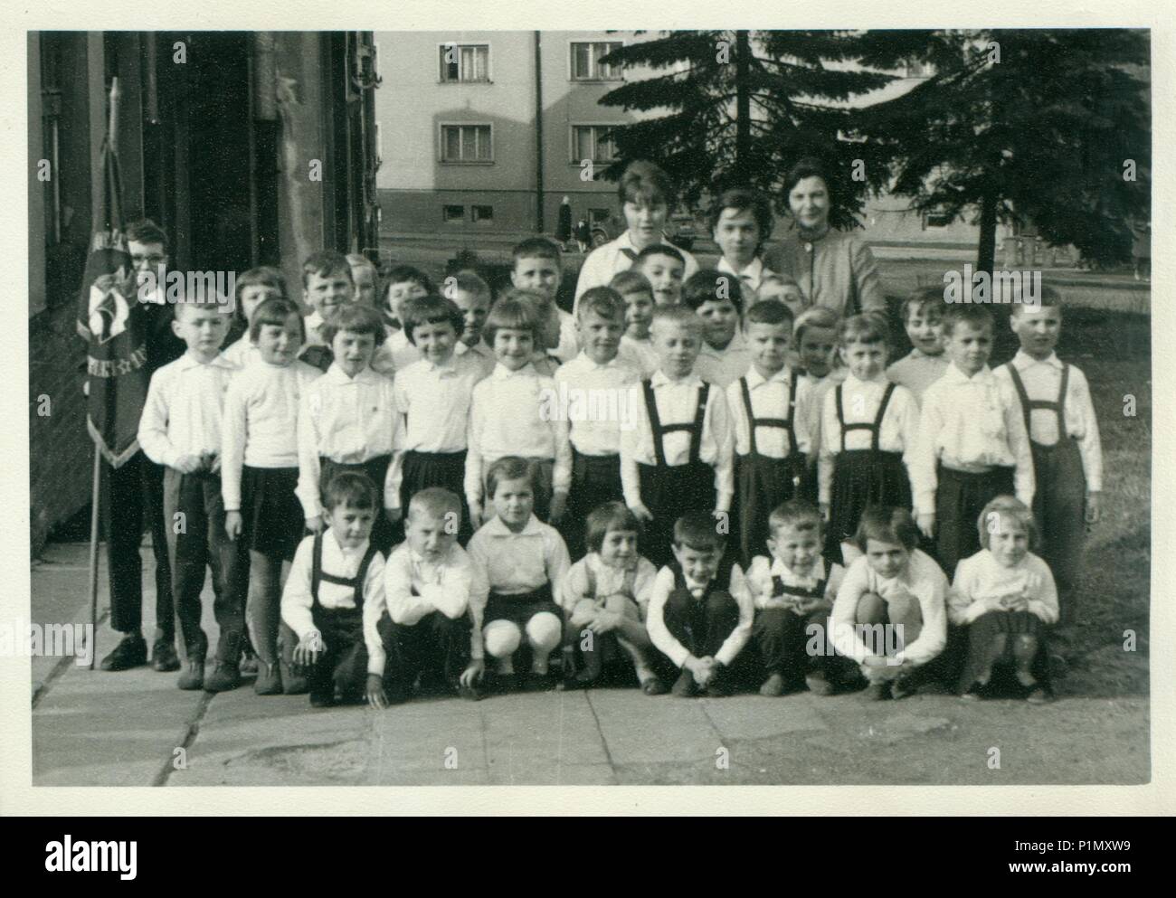 THE CZECHOSLOVAK SOCIALIST REPUBLIC - CIRCA 1960s: Retro photo shows small pupils and they female teachers (schoolmistresses) pose for photograper outside. Vintage black & white photography. Stock Photo