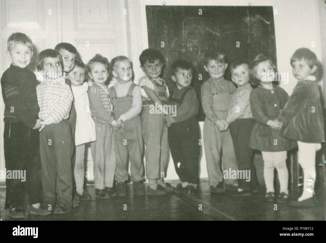 THE CZECHOSLOVAK SOCIALIST REPUBLIC - CIRCA 1960s: Retro photo shows small pupils in the classroom. Blackboard on the background.  Vintage black & white photography. Stock Photo