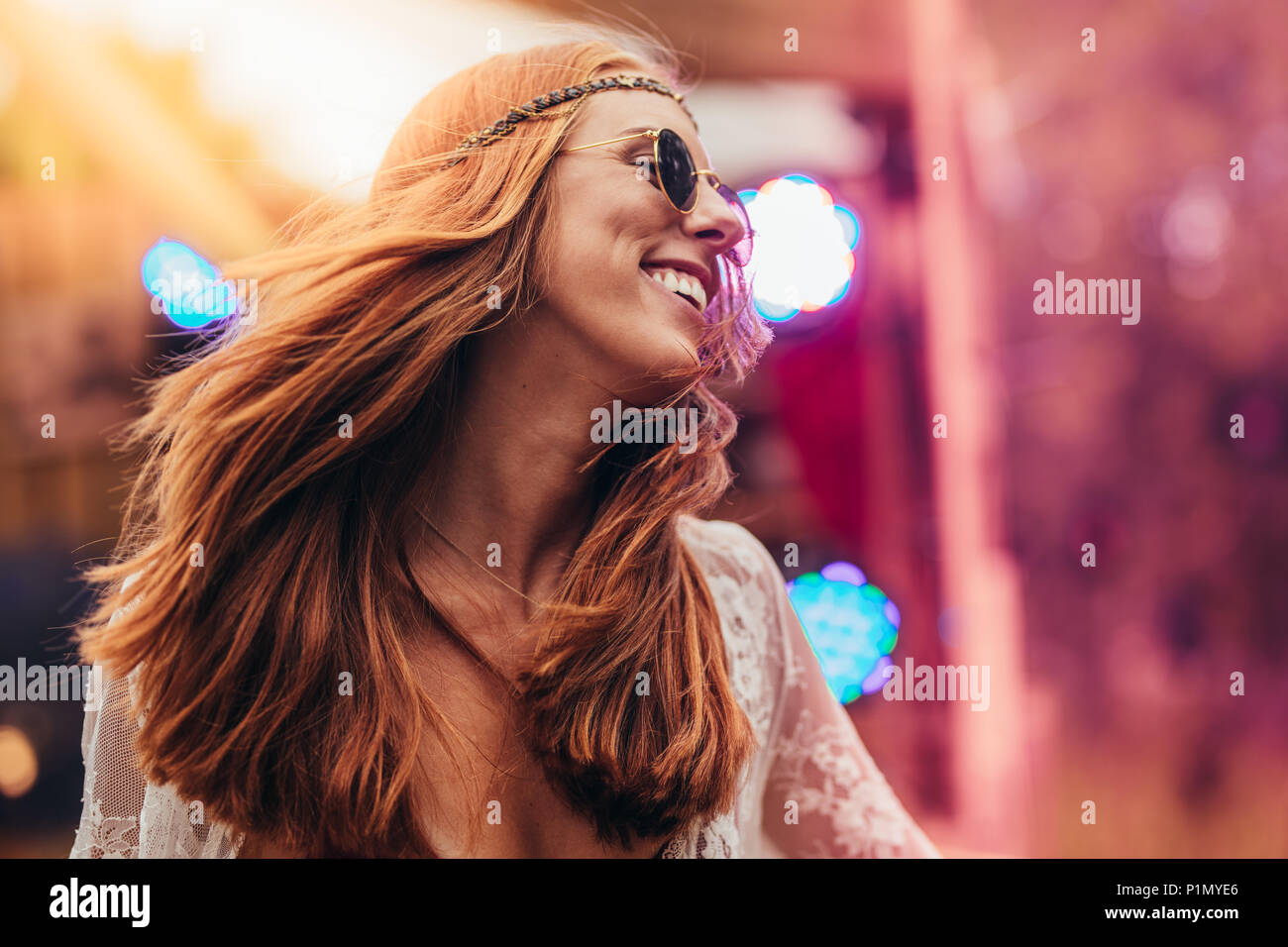 Beautiful young hippie woman enjoying at music festival outdoors. Woman in retro look dancing at music festival. Stock Photo