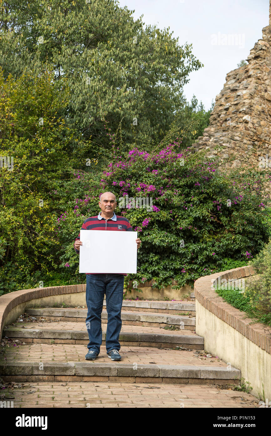 Man holding blank sign in the medieval city of Iglesias, Italy Stock Photo