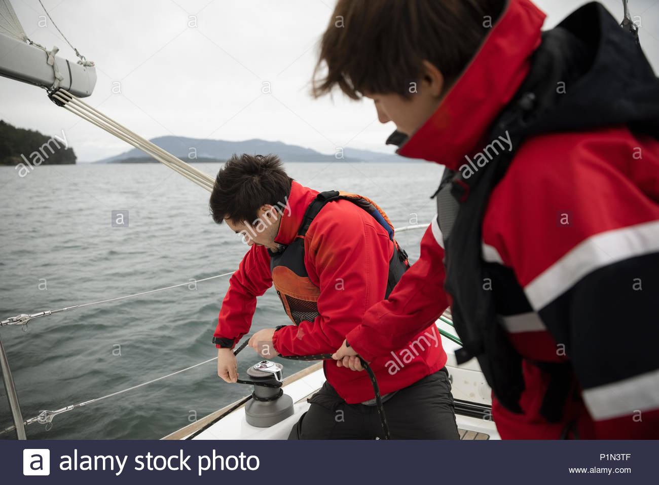 Sailing team adjusting equipment on sailboat on ocean Stock Photo Alamy