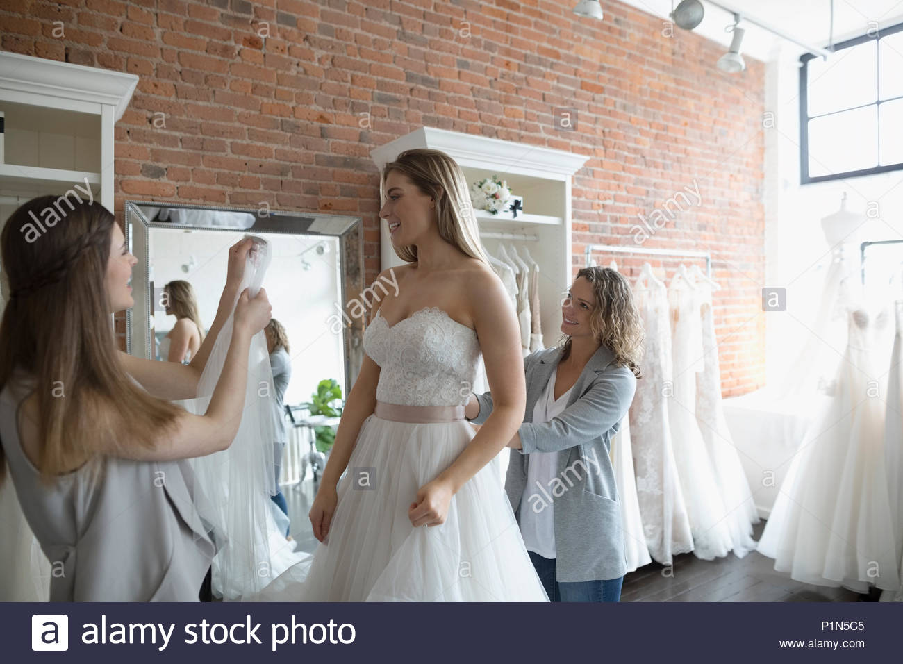 bride-and-friends-at-wedding-dress-fitting-in-bridal-boutique-stock