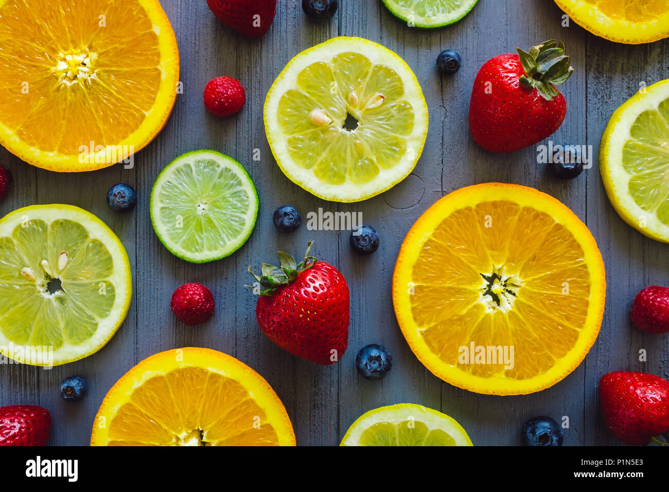 Mixed Sliced Oranges Lemons And Limes With Blueberries And Strawberries On Blue Table Stock Photo Alamy