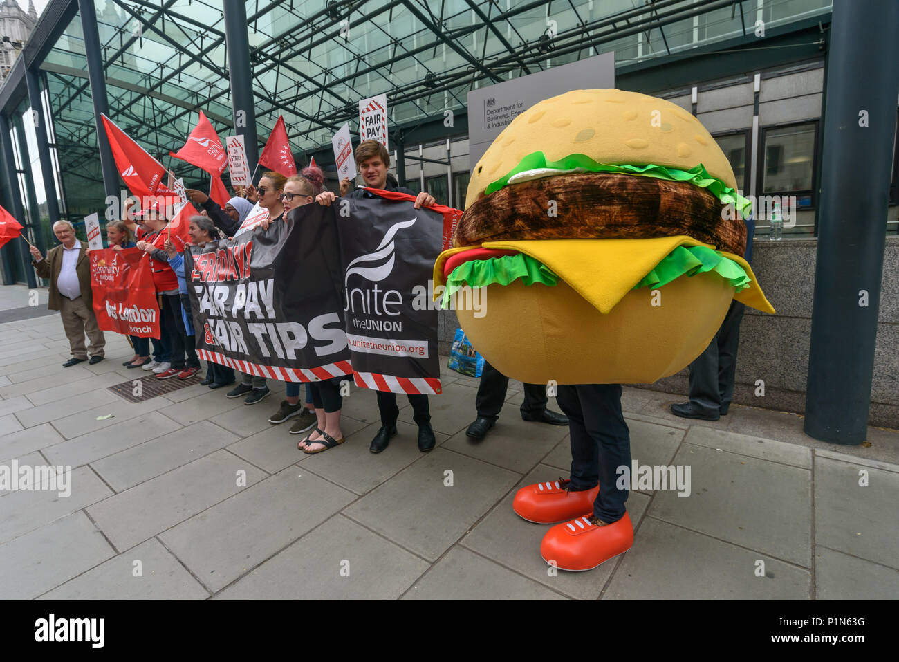 London, UK. 12th June 2018. Strikers from TGI Fridays, others from the Unite  Restaurant, Catering and Bar Workers Branch and Unite Community came to the Department of Business, Energy, Innovation and Skills with a man dressed as a giant burger to deliver a letter to business secretary Greg Clark calling on him to put an end to employers taking a part of the credit card tips that customers leave. Two years ago his predecessor Sajid Javid promised to tackle the problem but nothing has been done. Credit: Peter Marshall/Alamy Live News Stock Photo