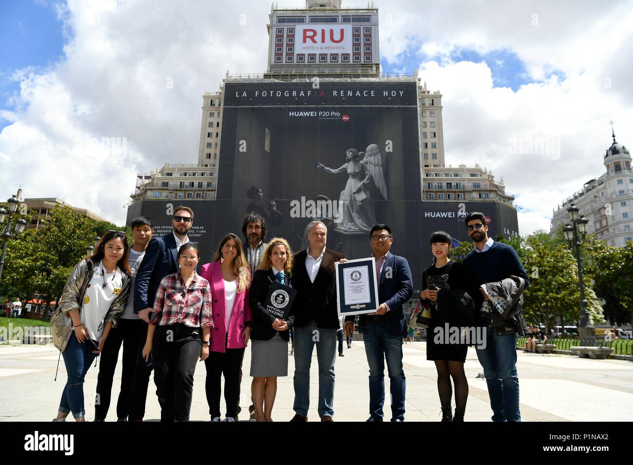 Madrid, Spain. 12th June, 2018. People pose for photos with the Guinness World Record certificate in front of the Huawei P20 Pro advertisement outside a building in Madrid, Spain, June 12, 2018. Huawei on Tuesday received a Guinness World Record certificate for 'the largest scaffold banner in the world'. Credit: Guo Qiuda/Xinhua/Alamy Live News Stock Photo