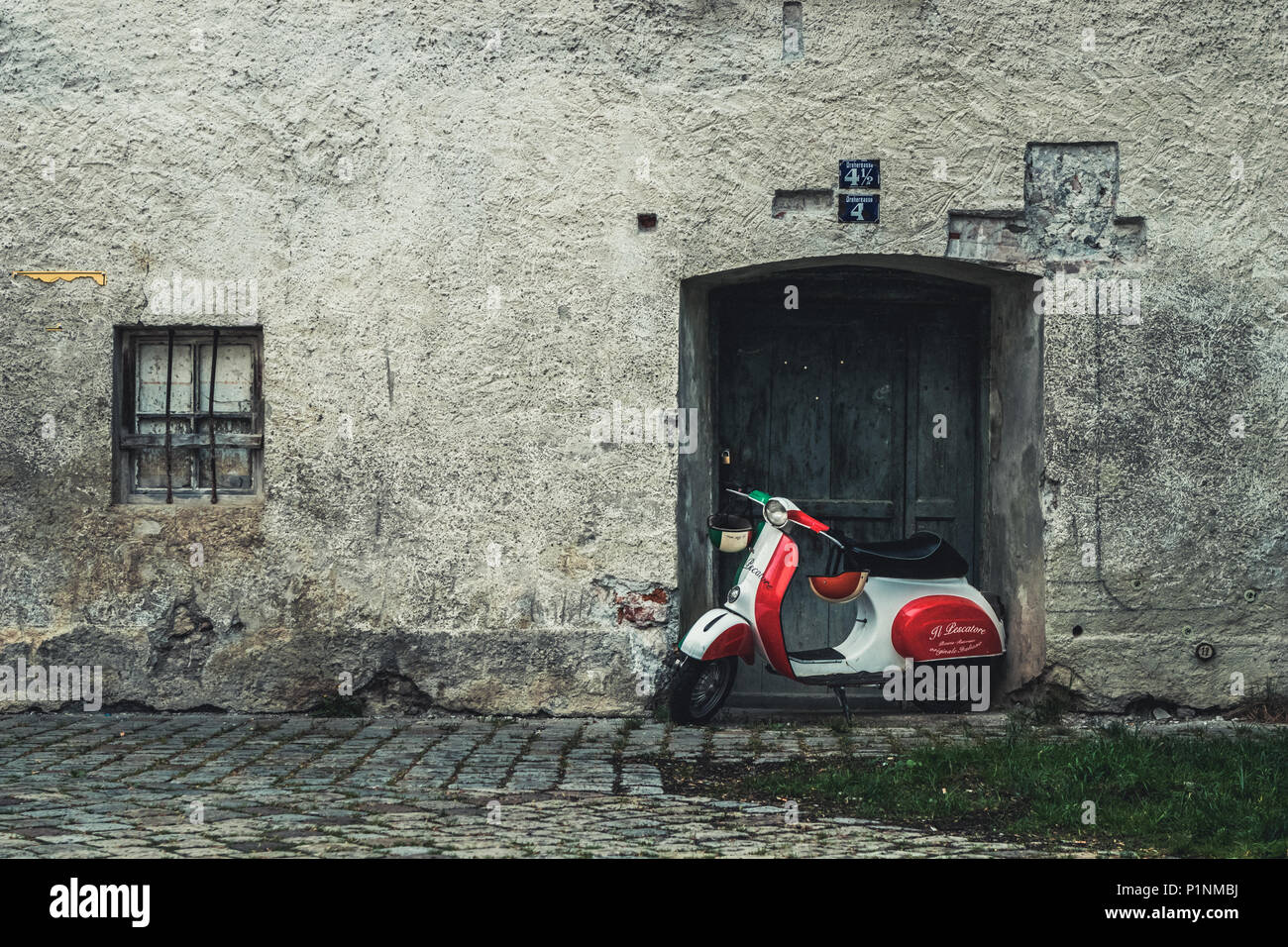 Füssen, Germany - May 10, 2018: Classic red white and green colored Piaggio Vespa scooter motorcycle standing on a cobblestone covered street at the d Stock Photo