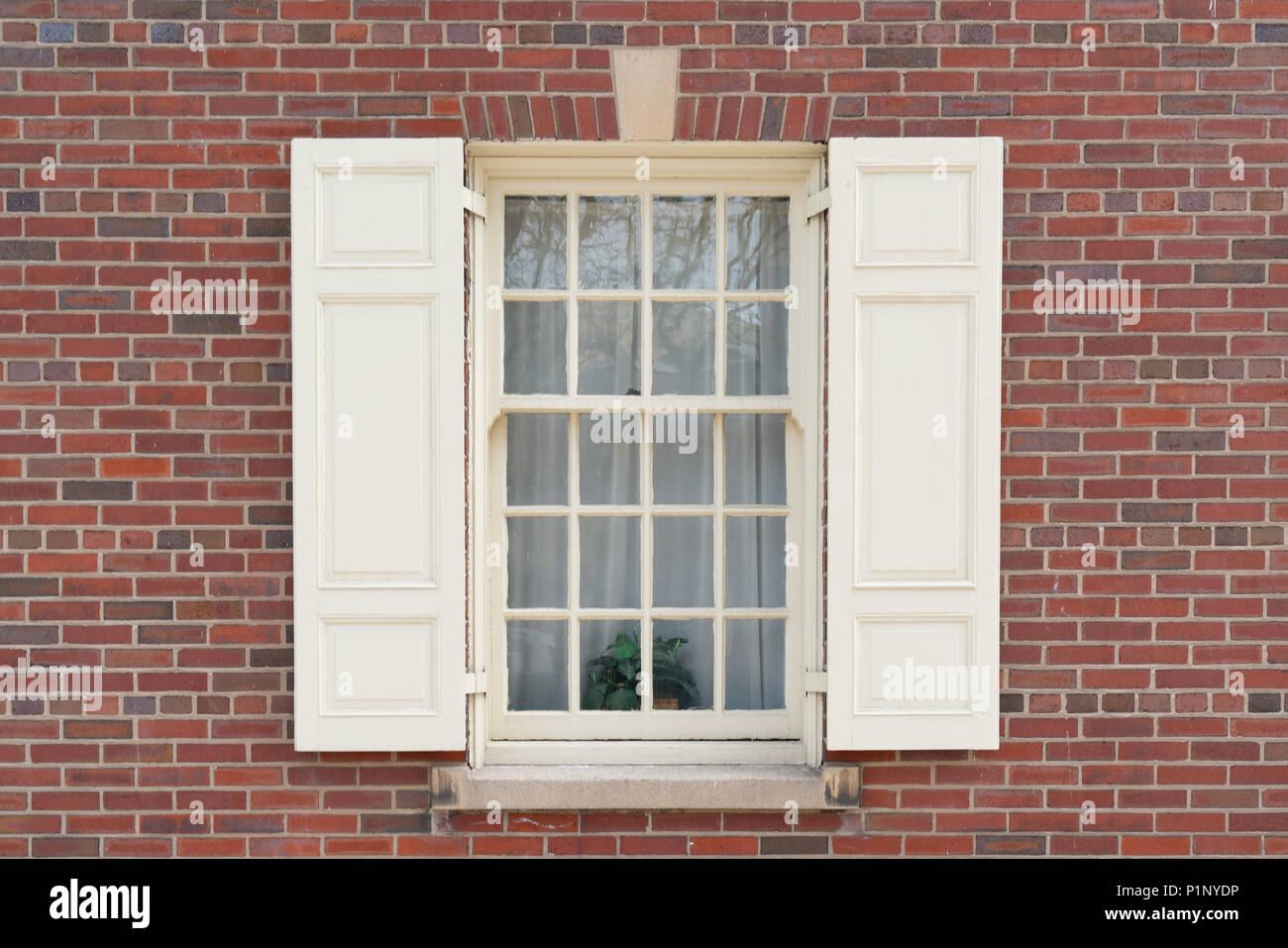 Old colonial window with shutters on historic brick building Stock