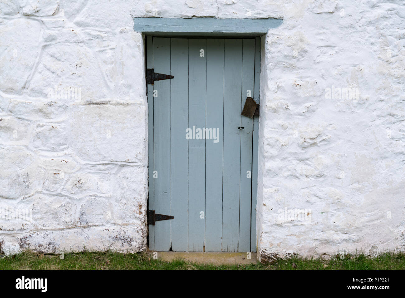 Old Blue weathered wooden door on a whitewashed stone building Stock Photo