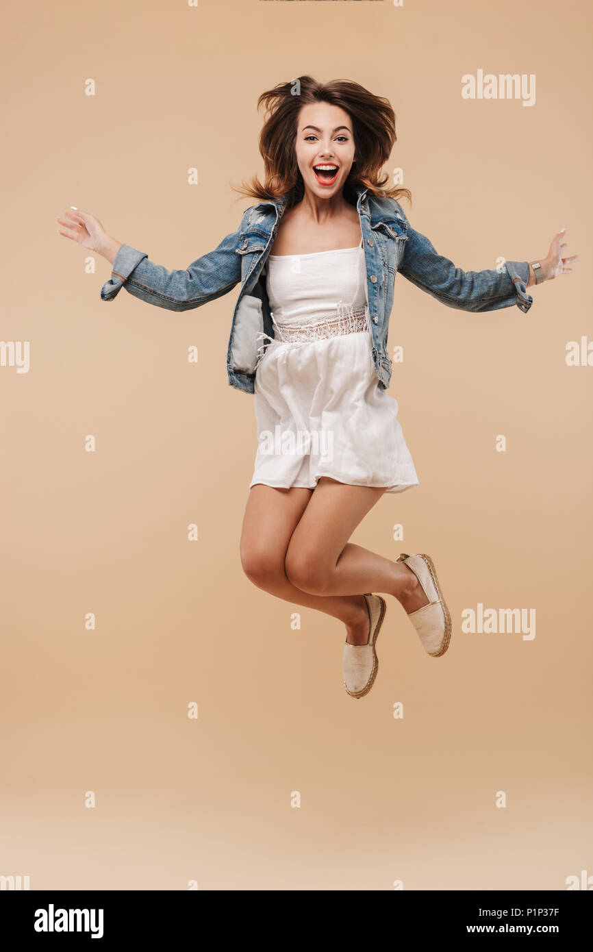 Full length portrait of a cheerful young girl in summer clothes jumping ...