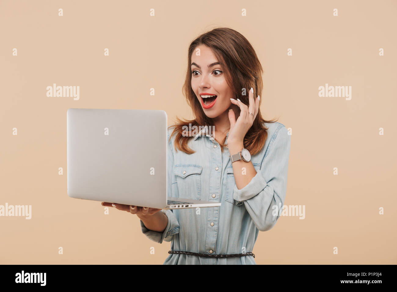 Portrait of a surprised young girl in summer clothes looking at laptop ...