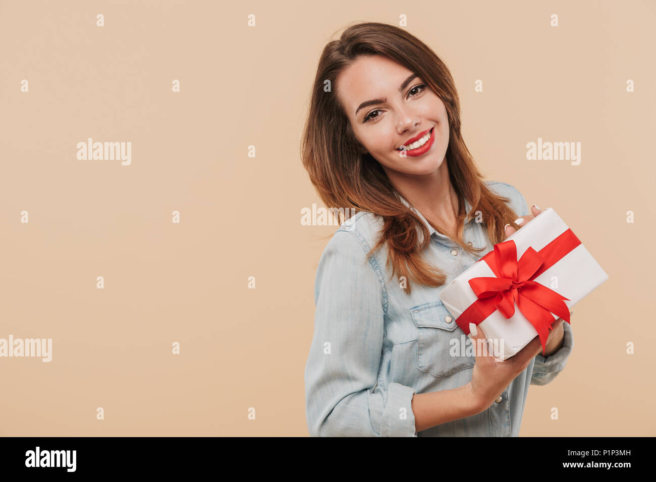 Portrait of a smiling young girl holding present box isolated over ...