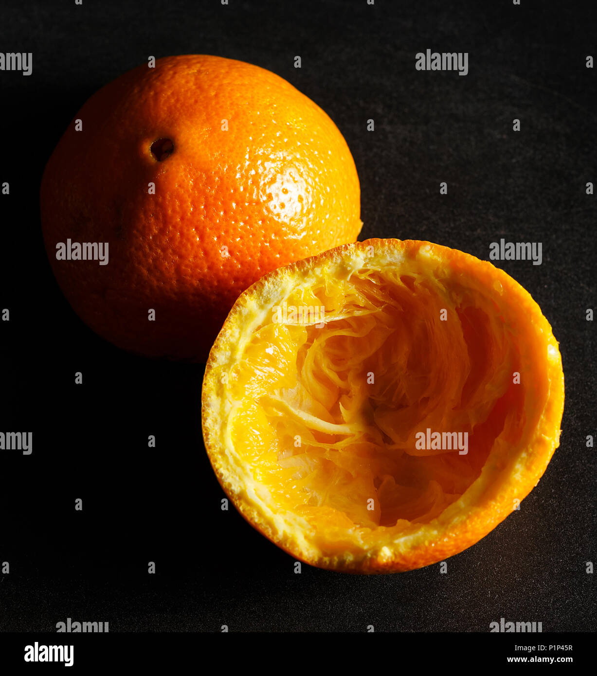 Used orange skins with dramatic light on black background. Square image. Stock Photo