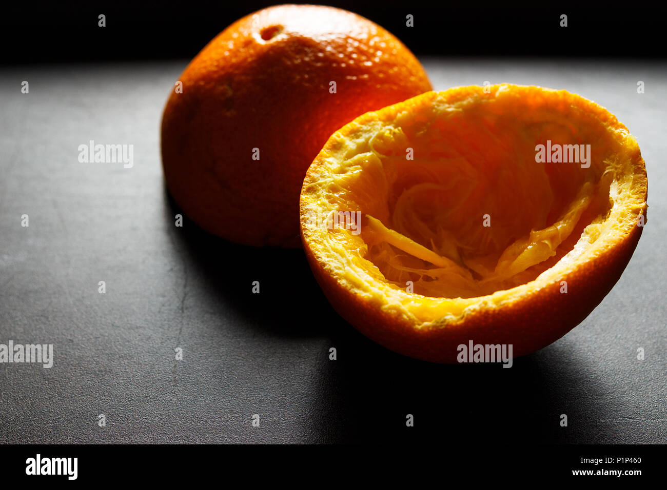 Used orange skins with dramatic light on black background. Horizontal image. Stock Photo