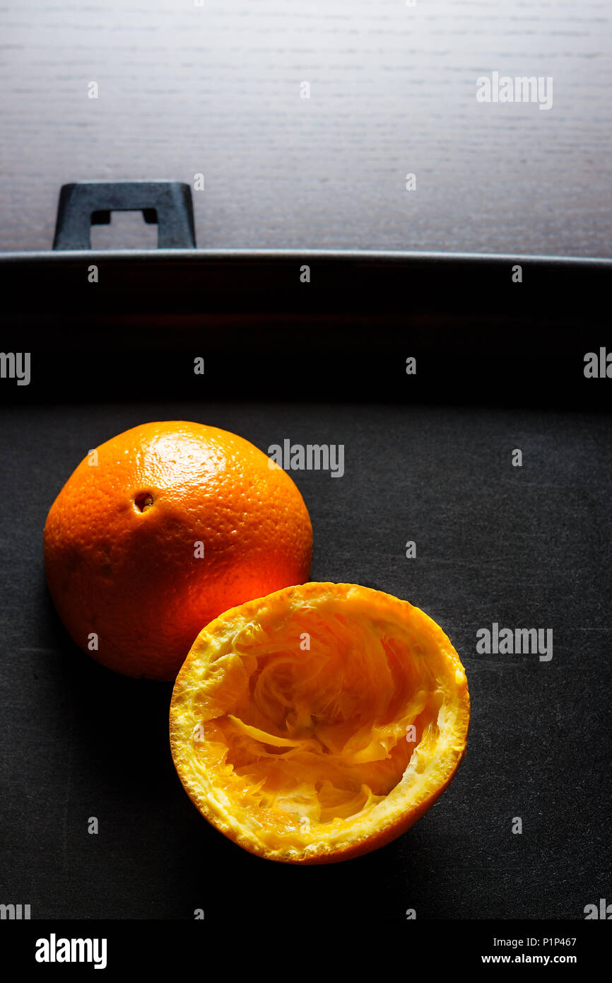 Used orange skins with dramatic light on black background. Vertical image. Stock Photo