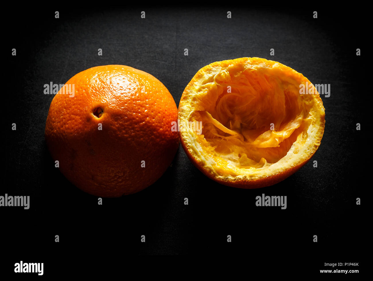 Used orange skins with dramatic light on black background. Horizontal image. Stock Photo