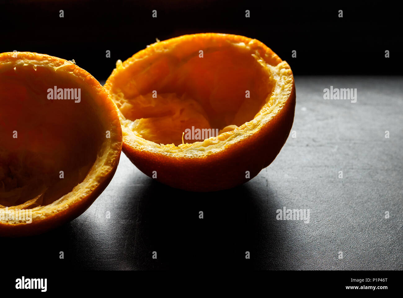 Used orange skins with dramatic light on black background. Horizontal image. Stock Photo